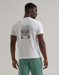 Uomo di spalle che indossa una maglietta bianca con una scatola di pastelli Crayola colorati e il logo "Lee" sulla schiena, abbinata a pantaloni a righe verdi.