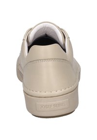 Beige leather sneaker featuring a rounded toe, smooth texture, subtle stitching, and a branded tab on the heel for added detail.