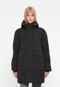 Svart polstret parka-jakke med høy krage, justerbar hette og frontlommer. Har en glatt tekstur og rett snitt.