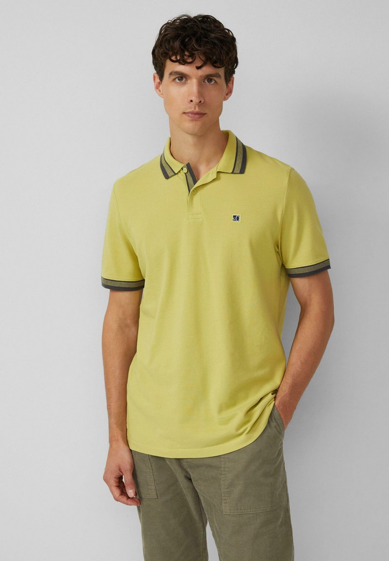 Korte mouwen polo shirt in lichtgele katoen met een donkere gestreepte kraag en manchetten, met een klein logo op de linkerborst.