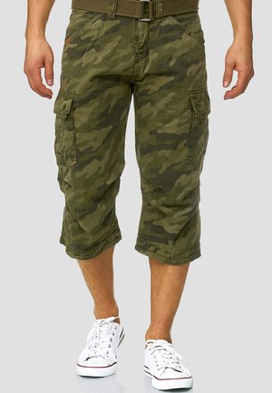 Kamuflasje cargo shorts i olivengrønn stoff, med flere lommefester, oppbrettede sømmer og beltestropper, kombinert med hvite joggesko.