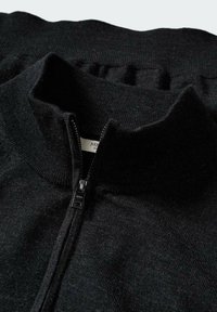 Czarny sweter na zamek z wysokim kołnierzem, z prążkowaną fakturą i gładkim zamkiem błyskawicznym. Miękki materiał o minimalistycznym designie.