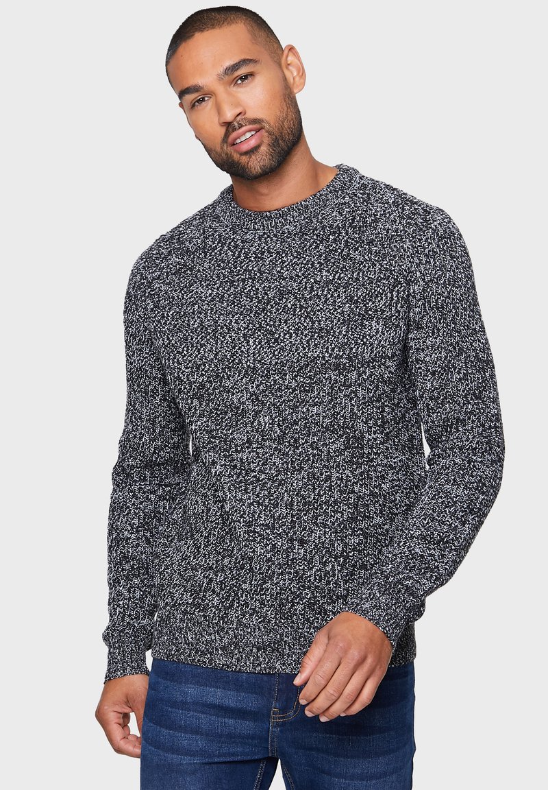 Maglione grigio e bianco a maglia con scollo a girocollo, maniche lunghe e motivo testurizzato, abbinato a jeans in denim blu.
