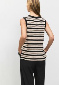 Sleeveless top in beige and black horizontal stripes, featuring a round neckline, side slits, and a relaxed fit. Textured fabric.