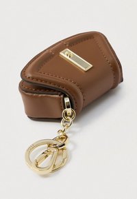 Un suport pentru chei din piele maro, pliat, cu un inel de cheie și un clip din metal de culoare aurie, pe un fundal deschis.