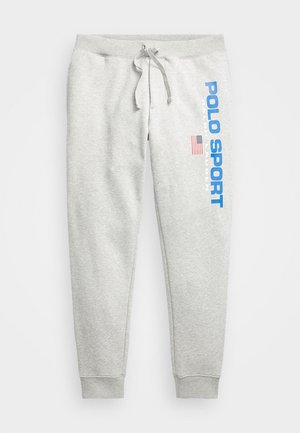 Jasnoszare spodnie dresowe z troczkiem w pasie, ściągaczami przy kostkach i niebieskim tekstem "Polo Sport Ralph Lauren" oraz amerykańską flagą na lewej nodze.