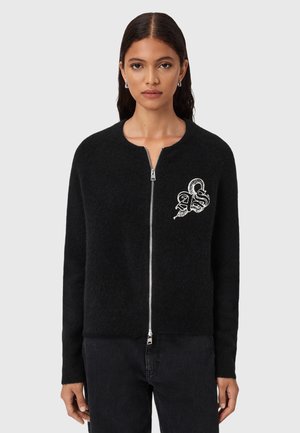 Cardigan nero con zip e collo rotondo, realizzato in tessuto morbido. Presenta una superficie testurizzata e un design grafico bianco sul petto.