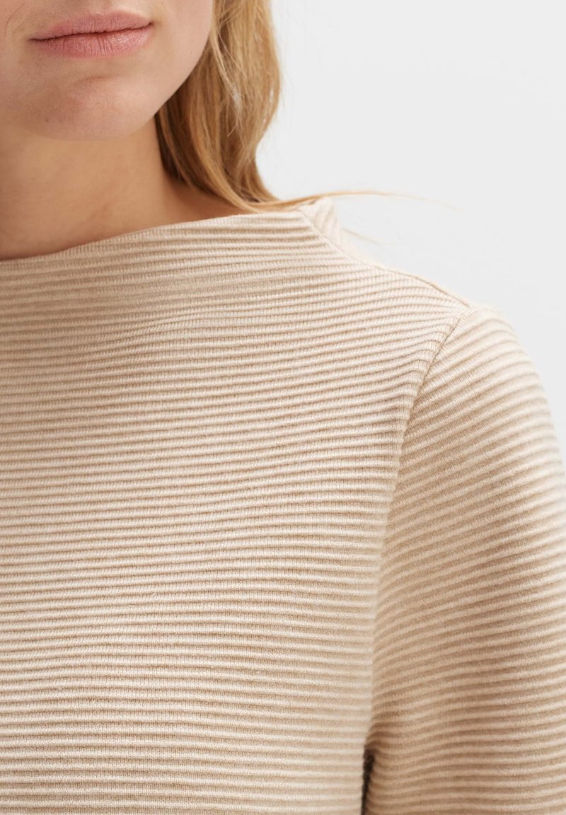 Beige gestreifter Oberteil mit Bootsausschnitt, aus einem weichen, strukturierten Stoff, der dezente, horizontale Rippen über die Oberfläche aufweist.