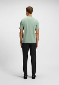 Light green short-sleeve shirt with a crew neckline, paired with black straight-leg trousers and black shoes. Simple, clean design.