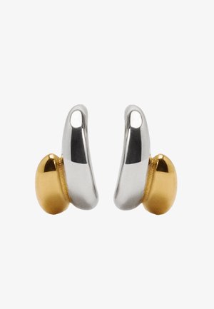 Srebrno-złote metalowe kolczyki o zakrzywionym kształcie, z błyszczącym srebrnym wykończeniem i gładkim, zaokrąglonym złotym akcentem.