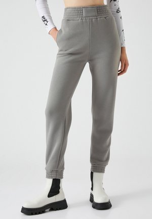 Grå joggers i mjukt material, med en elastisk midja, avsmalnande mudd och sidofickor. Matchade med vita ankle boots.
