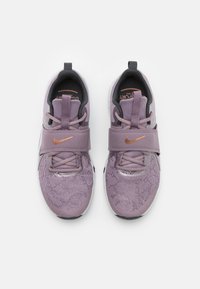 Fioletowe buty sportowe z siateczkową cholewką, wyściełanym kołnierzem wokół kostki i wyraźnym paskiem. Ozdobione metalicznym logo oraz fakturą na powierzchni.