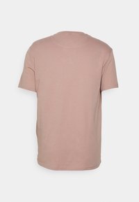 Camiseta de algodón rosa pálido con mangas cortas, cuello redondo y una textura suave. Diseño trasero simple y sin costuras, sin adornos.