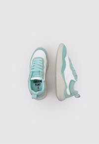 Baskets de sport en blanc et vert d'eau clair avec une semelle en caoutchouc texturée, un design à lacets et un message "IL N'Y A PAS DE PLAN B" à l'intérieur.