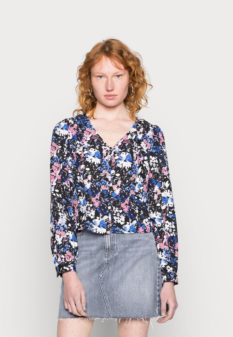 Blusa floral com fundo preto, apresentando padrões em rosa, azul e branco. Tem um decote em V, mangas longas e um design cropped.