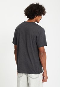 Grijze t-shirt met korte mouwen, gemaakt van zachte stof met een relaxed fit. De achterzijde toont een ronde hals en een gladde textuur zonder zichtbare logo's.