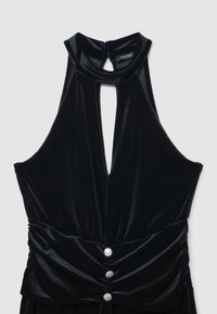 Top senza maniche in velluto nero con collo alto, apertura a chiave frontale e tre bottoni decorativi in strass in vita arricciata.