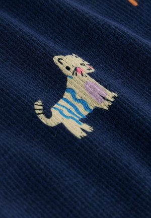 Tamsios mėlynos spalvos audinys su stilizuotu katinu, dryžuotu kreminės, mėlynos ir rožinės spalvų juostelėmis; minkšta tekstūra ir žaismingi dizaino elementai.