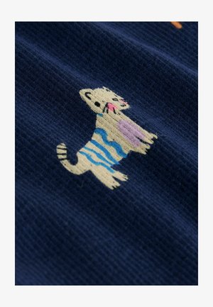 Marineblauer Stoff mit einer stilisierten Katze, die Streifen in Creme, Blau und Pink hat; weiche Textur und verspielte Designelemente.