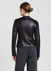 Veste en cuir noir au design ajusté, avec un col haut et des manches longues. Texture lisse avec une taille peplum et un dos ajusté.