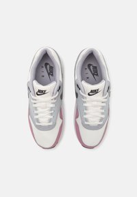 Nike Air tossud, millel on valge sussivõrk ja heledad hallid ning roosa aktsent, must logo ja valged paelad.