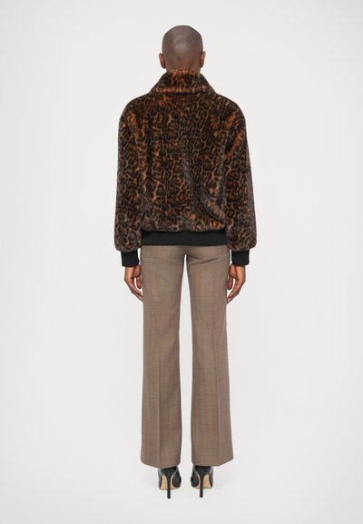Casaco de pêlo falso com estampado de leopardo, com colarinho alto, punhos e bainha em malha preta, combinado com umas calças xadrez castanhas e saltos pretos.