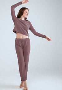 Gestreepte pyjama set in rood en wit, met een cropped lange mouwen top en bijpassende strakke broek, gemaakt van zachte, lichte stof.