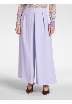 Lavendel wijde broek met frontplooien, gedragen met bruine pumps met puntige neus en een multikleurig, patroon langarmshirt.