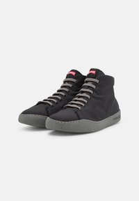 Adidași cu guler înalt din material textil negru, cu tălpi din cauciuc gri cu pete. Dispun de șireturi gri și un logo roșu al brandului la guler.