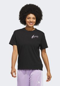 Čierne bavlnené tričko s krátkymi rukávmi a voľným strihom, na hrudi s malým ružovým logom Adidas. Kombinované s svetlofialovými nohavicami.