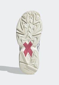 Vit gummisula på sneakers med en texturerad greppyta, prydd med en rosa korsdetalj och ett triangelmönster för bättre grepp.