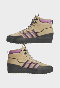 Beiga högsko sneakers med svart gummisula, svarta och lila ränder, texturerad kanvastoppning och metallögon med grå snörning.