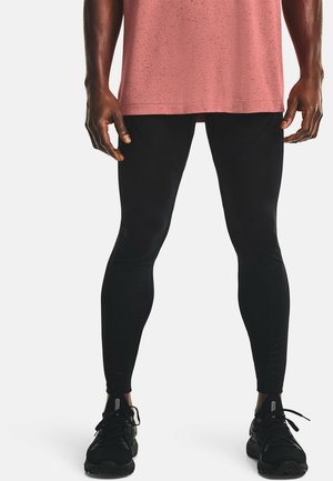 Schwarze sportliche Leggings mit glatter Textur und durchbrochenen Akzenten. Kombiniert mit einem kurzärmeligen, rosa melierten T-Shirt und schwarzen Turnschuhen.