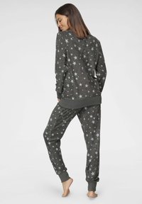 Gray lounge set with star patterns. Sweatshirt has a round neck and ribbed cuffs. Pants feature elastic waistband and ribbed ankle cuffs.