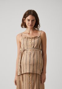 Beige stripete topp laget av teksturert stoff, med en volangkrage, lukking med treknapper og et knyttet midje-design. Lettvektsdesign.