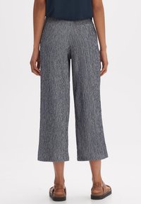 Blå och vita strukturerade vida byxor med medelhög midja och bakficka, kombinerat med bruna sandaler.