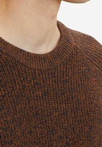 Maglione lavorato a maglia marrone con un motivo testurizzato. Presenta un collo rotondo a coste e maniche raglan corte. Il materiale sembra morbido e caldo.
