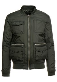 Vadderad bomberjacka i mörkgrön, med dragkedja framtill, två bröstfickor och två sidofickor med dragkedja. Ribbad krage och ärmslut.