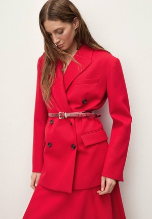 Sacou roșu cu două rânduri de nasturi, realizat dintr-un material structurat, cu nasturi negri și talie cu curea decorată cu un accent cu imprimeu de șarpe. Detaliu cu buzunar plat.