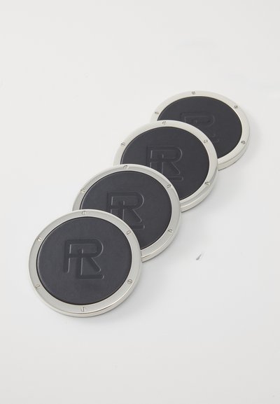 Set od četiri okrugla podmetača s teksturiranom crnom kožom i srebrnim metalnim rubovima. Svaki ima urezani logo "R".