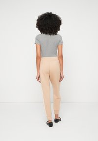 Pelēks īsām piedurknēm tops apvienots ar bēšiem sporta biksēm ar sānu mežģīņu akcentiem. Bikses ir sašaurinātas un ar ribotām piedurknēm.