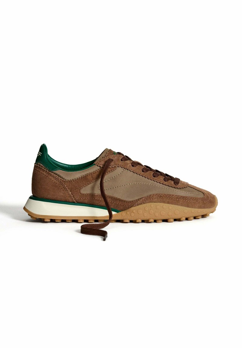 Sneaker atletico in camoscio e pelle marrone con dettagli verdi, lacci marroni, suola testurizzata e intersuola bianca. Vista laterale.