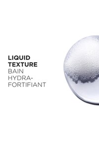 Gel transparente con superficie burbujeante, mostrado en un recipiente redondo. Texto superpuesto menciona "Textura Líquida" y "Bain Hydra-Fortifiant."