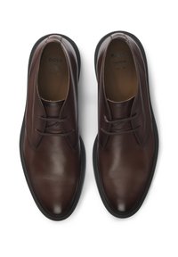 Rudos odinės suknelės batai su lygiu paviršiumi, apvaliu pirštu ir minimaliais raišteliais. Juoda guminiu padas su elegantišku dizainu.