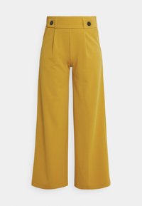 Weite Hosen in einem lebhaften Senfgelb. Hergestellt aus glattem Stoff, mit zwei schwarzen Knöpfen und vorderen Falten für zusätzliche Details.