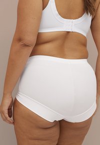 Weiße Unterwäsche aus Baumwollmischung mit einer glatten Textur und hohem Bund, ausgestattet mit einem breiten elastischen Taillenbund und ohne sichtbare Nähte.