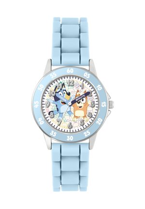 La montre avec bracelet en silicone bleu présente un cadran rond avec une lunette argentée. Le cadran affiche des personnages de dessin animé avec des indicateurs d'heure et de minute, sur un fond pastel.