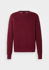 Pull col rond bordeaux en maille texturée, avec manches longues et poignets côtelés. Petit logo sur la poitrine. Coupe classique.
