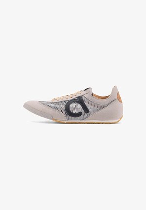 Lichtgrijze sneaker met mesh-zijden, beige veters, rubberen zool en zwart "ci"-logo aan de buitenkant.