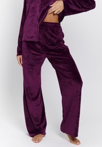 Velvet tvådelat lounge-set i djup lila med en knapp-up topp och vida byxor med elastisk midja. Mjuk textur.